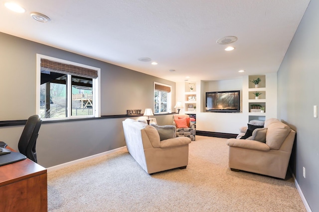 carpeted living room with recessed lighting, built in shelves, and baseboards