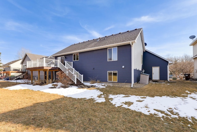 snow covered property with stairway, a lawn, and a deck