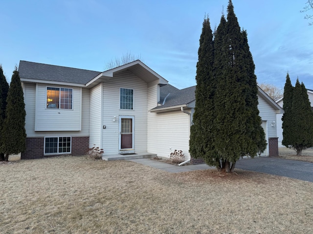 view of front of home with aphalt driveway, brick siding, a garage, and a shingled roof