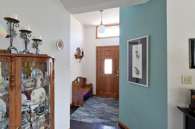 foyer with baseboards, a textured ceiling, and wood finished floors