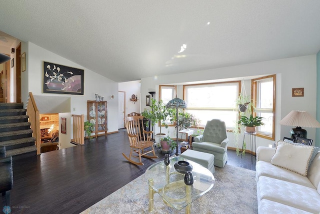 living room featuring vaulted ceiling, stairway, wood finished floors, and a textured ceiling