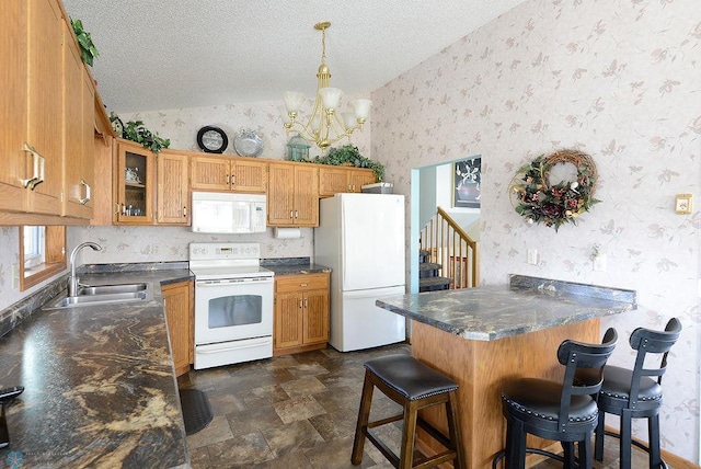 kitchen with dark countertops, wallpapered walls, vaulted ceiling, white appliances, and a sink