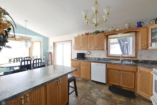 kitchen with a sink, white appliances, dark countertops, and plenty of natural light