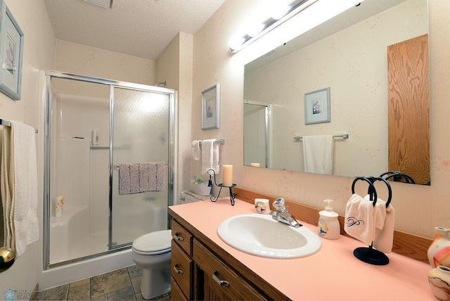 bathroom featuring vanity, a shower stall, stone finish floor, a textured ceiling, and toilet