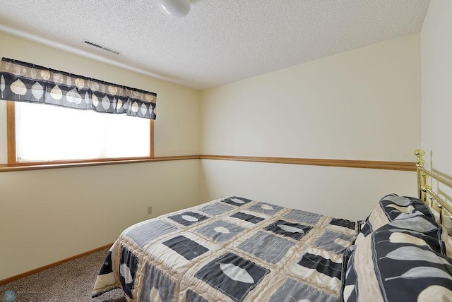 carpeted bedroom with visible vents, a textured ceiling, and baseboards