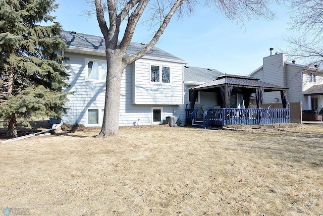 rear view of house featuring a gazebo, central air condition unit, and a lawn