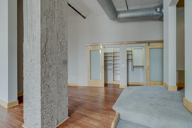 bedroom with baseboards, a high ceiling, and wood finished floors