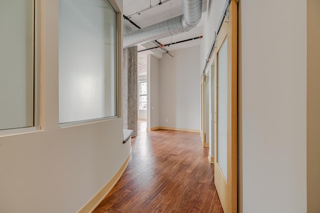 hall with a barn door, baseboards, and wood finished floors