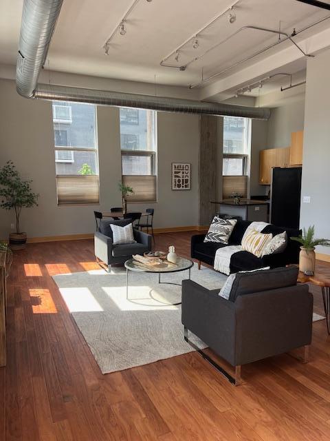 living area featuring light wood-style flooring, rail lighting, and baseboards