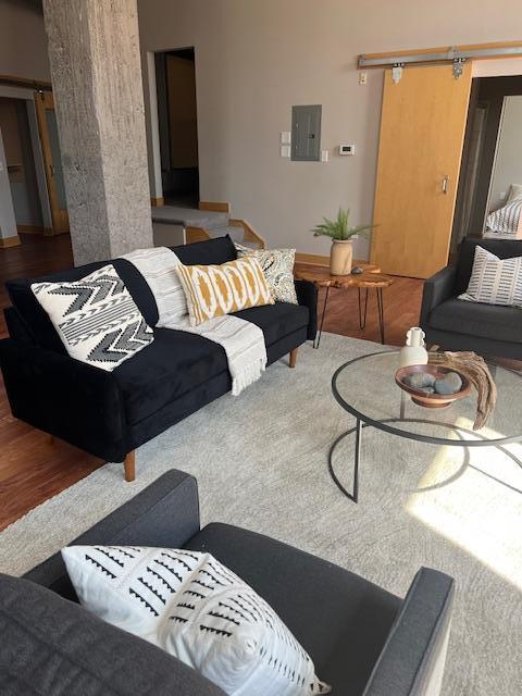 living area featuring electric panel, a barn door, and wood finished floors