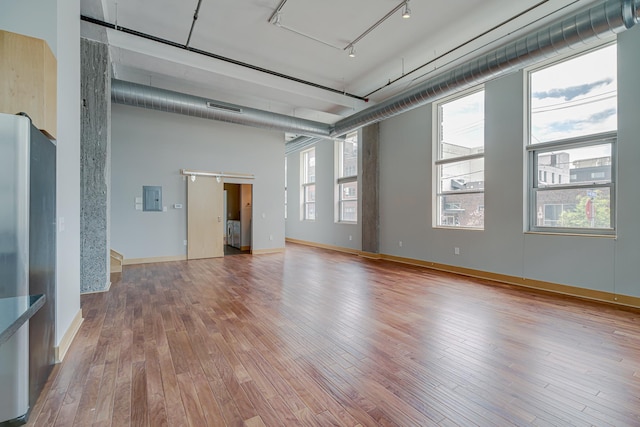 unfurnished room with electric panel, rail lighting, baseboards, and hardwood / wood-style floors