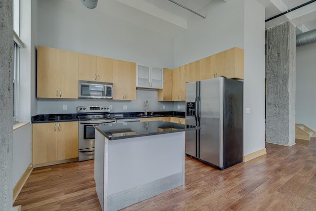 kitchen with stainless steel appliances, a high ceiling, and light brown cabinets