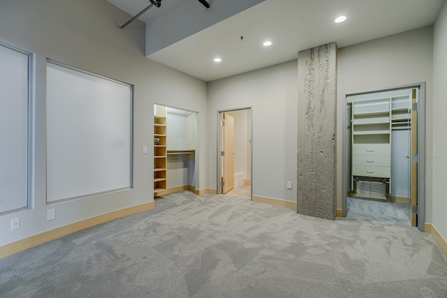 unfurnished bedroom featuring carpet, baseboards, recessed lighting, a closet, and a walk in closet