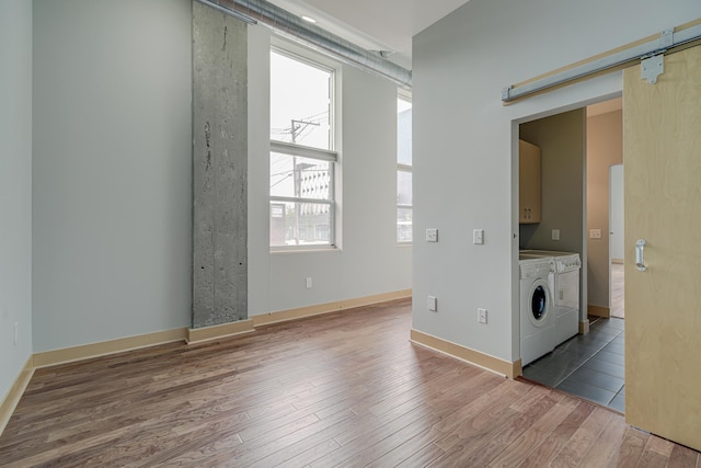 interior space featuring baseboards, a barn door, wood finished floors, cabinet space, and independent washer and dryer