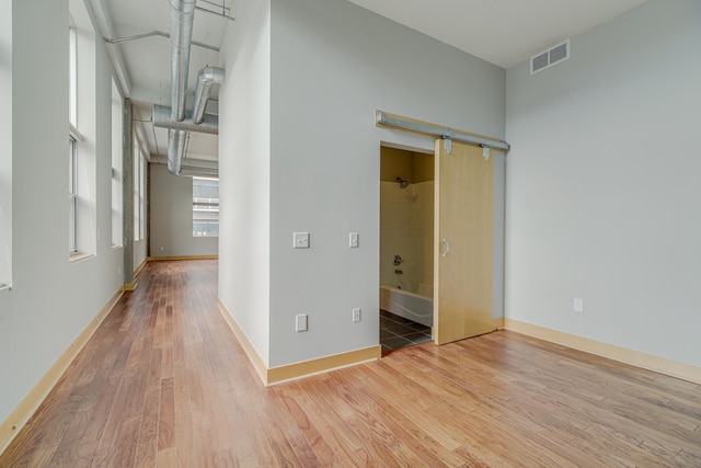 interior space featuring visible vents, a barn door, baseboards, and wood finished floors