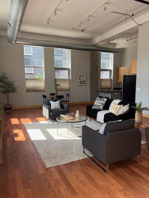 living room with rail lighting, baseboards, and light wood-type flooring