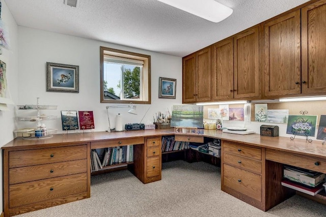 office space featuring built in study area, light carpet, and a textured ceiling