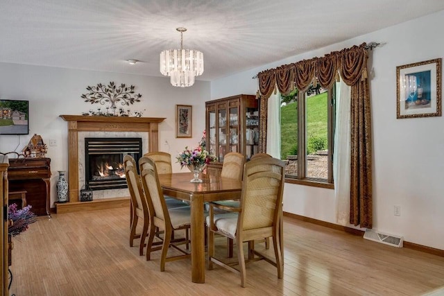 dining room with visible vents, a fireplace, light wood-type flooring, and baseboards