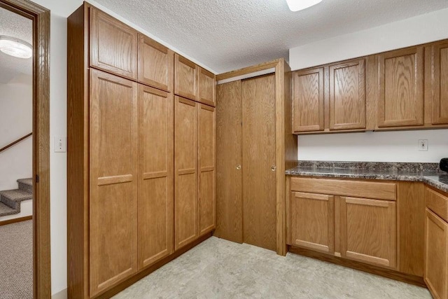 kitchen featuring dark countertops, brown cabinets, and a textured ceiling