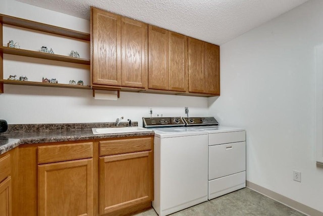 laundry room with washer and dryer, a sink, a textured ceiling, cabinet space, and baseboards