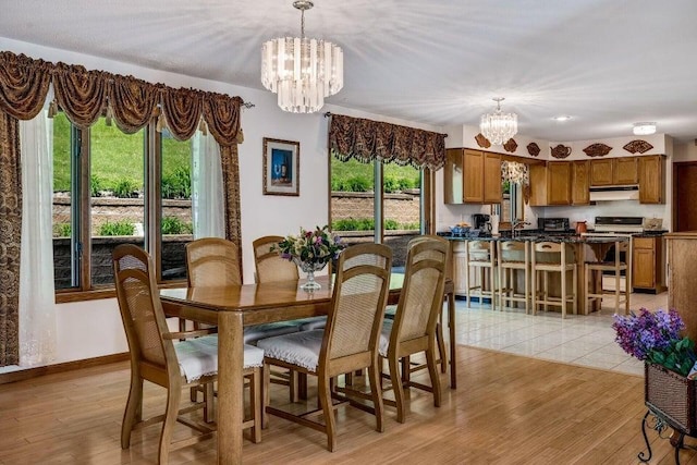 dining area featuring light wood-style flooring, baseboards, and an inviting chandelier