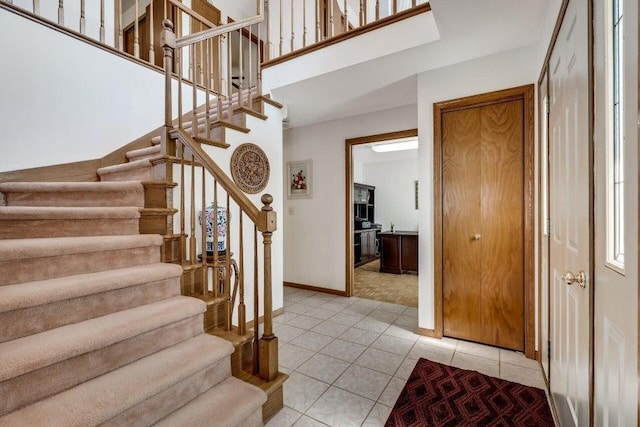 entrance foyer featuring light tile patterned floors, baseboards, and stairs