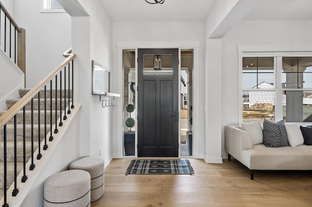 foyer with stairway, baseboards, and wood finished floors