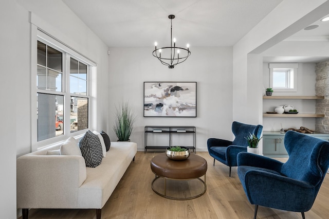 living area with baseboards, an inviting chandelier, and wood finished floors