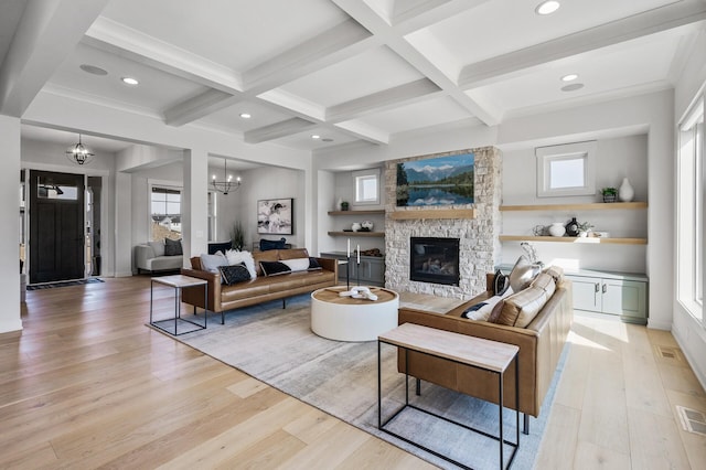 living room with a stone fireplace, beam ceiling, light wood-style flooring, and a notable chandelier