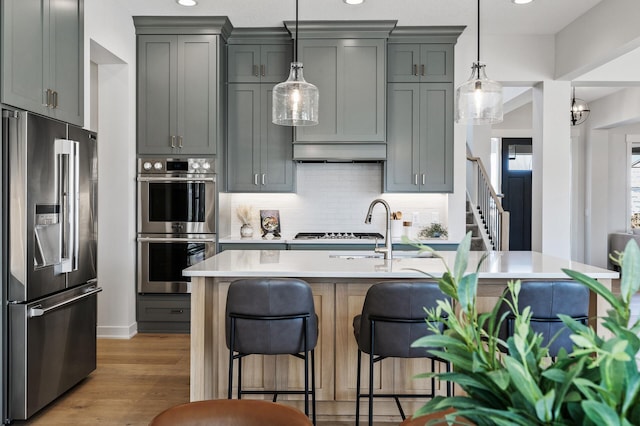 kitchen with a kitchen bar, light countertops, gray cabinets, and appliances with stainless steel finishes