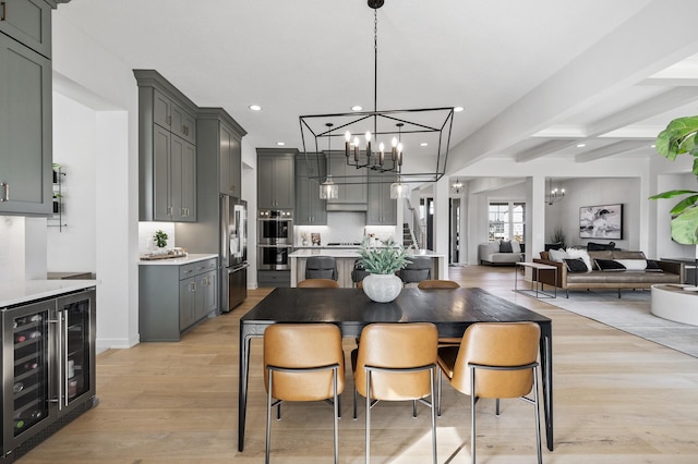 dining area featuring beam ceiling, light wood-style flooring, recessed lighting, wine cooler, and a chandelier