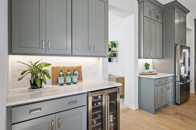 bar with light wood finished floors, tasteful backsplash, wine cooler, high quality fridge, and a bar