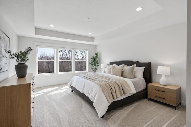 bedroom with a tray ceiling, recessed lighting, and light colored carpet