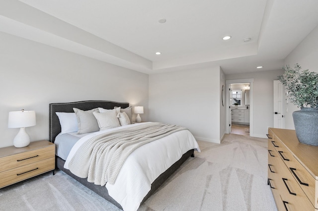 bedroom with baseboards, recessed lighting, ensuite bathroom, a raised ceiling, and light colored carpet