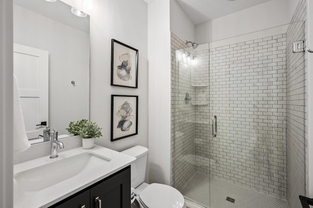 bathroom with a stall shower, toilet, and vanity