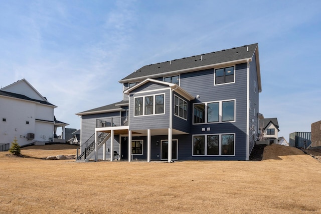 rear view of property featuring stairway and a lawn