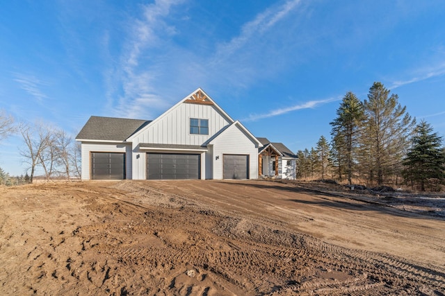 view of front facade with a garage, roof with shingles, and board and batten siding