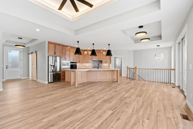 kitchen featuring stainless steel appliances, a raised ceiling, a barn door, and light brown cabinets