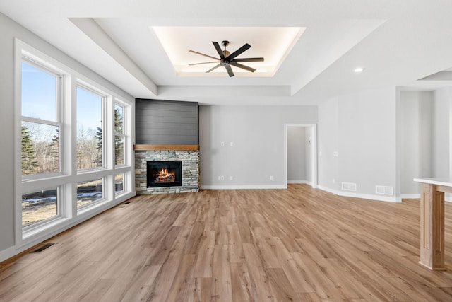 unfurnished living room with a tray ceiling, visible vents, and a fireplace