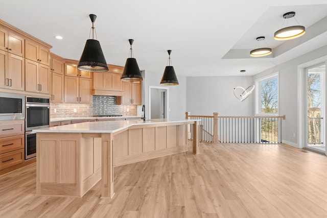 kitchen featuring light countertops, light wood-style flooring, tasteful backsplash, and appliances with stainless steel finishes