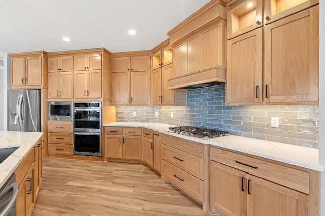 kitchen featuring light brown cabinets, light wood finished floors, appliances with stainless steel finishes, and light stone counters