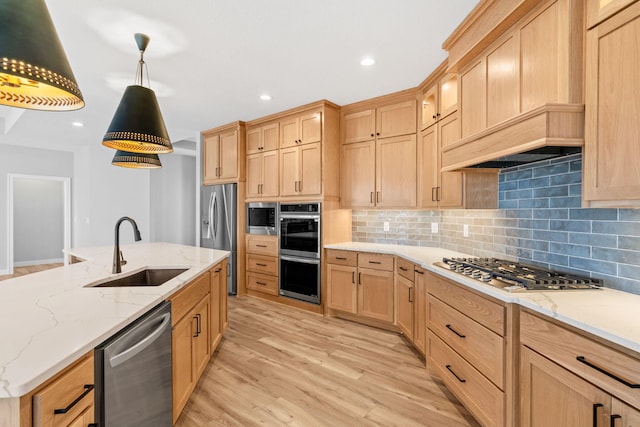 kitchen featuring light brown cabinetry, a sink, backsplash, stainless steel appliances, and light wood-style floors