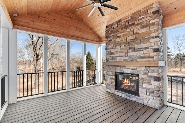 exterior space featuring wood ceiling, an outdoor stone fireplace, lofted ceiling, and a ceiling fan