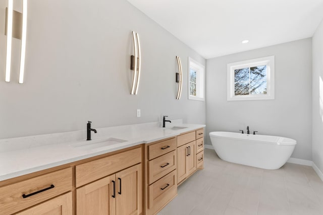 bathroom with a sink, baseboards, a soaking tub, and double vanity