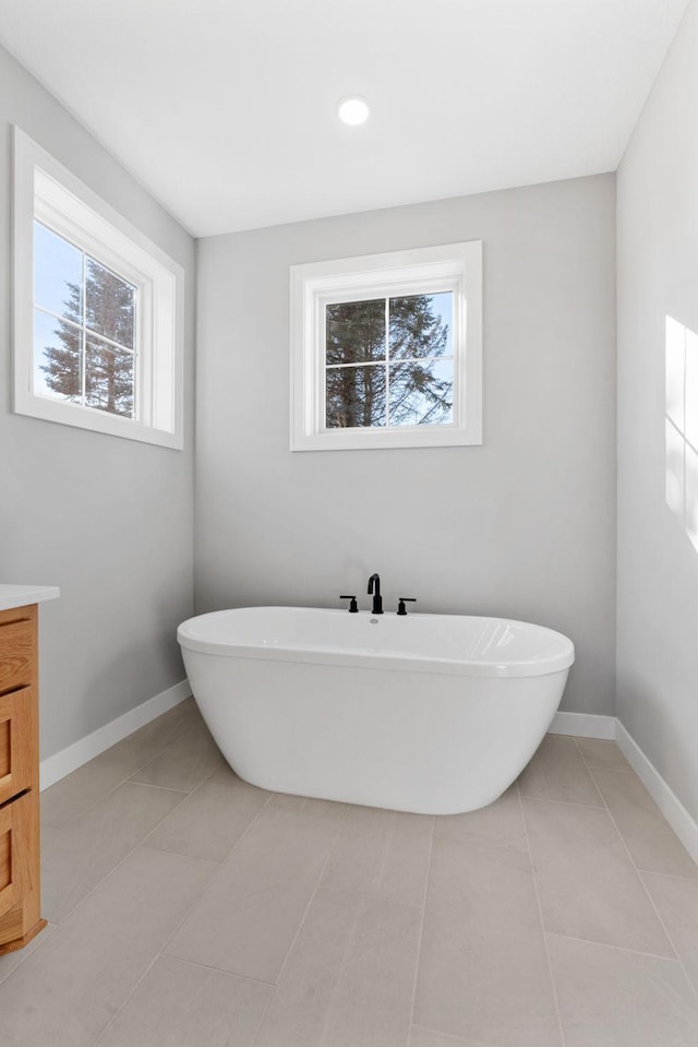 bathroom featuring vanity, tile patterned floors, baseboards, and a freestanding bath