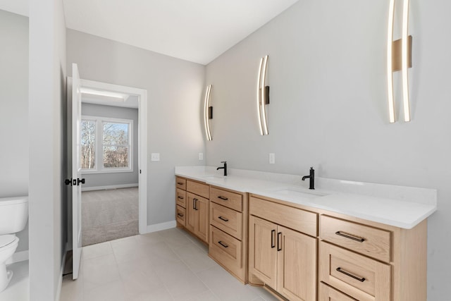 full bathroom with double vanity, toilet, baseboards, and a sink