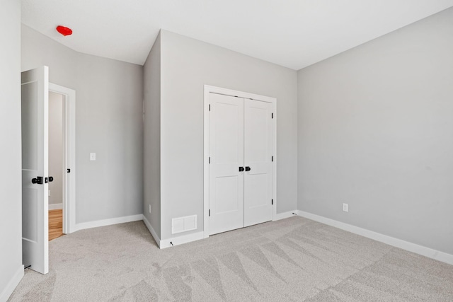 unfurnished bedroom featuring a closet, visible vents, baseboards, and carpet floors