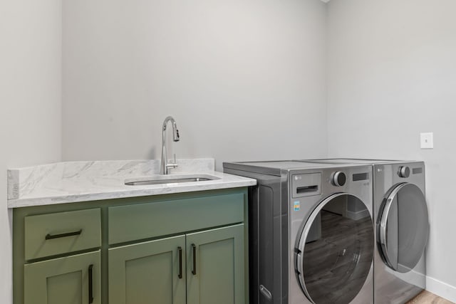 clothes washing area with a sink, cabinet space, separate washer and dryer, and light wood finished floors