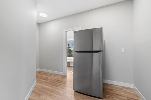 interior space with light wood-type flooring, freestanding refrigerator, and baseboards