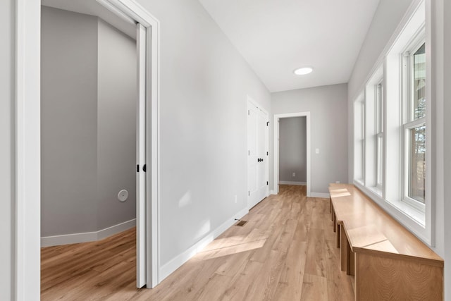 hall with baseboards and light wood-type flooring